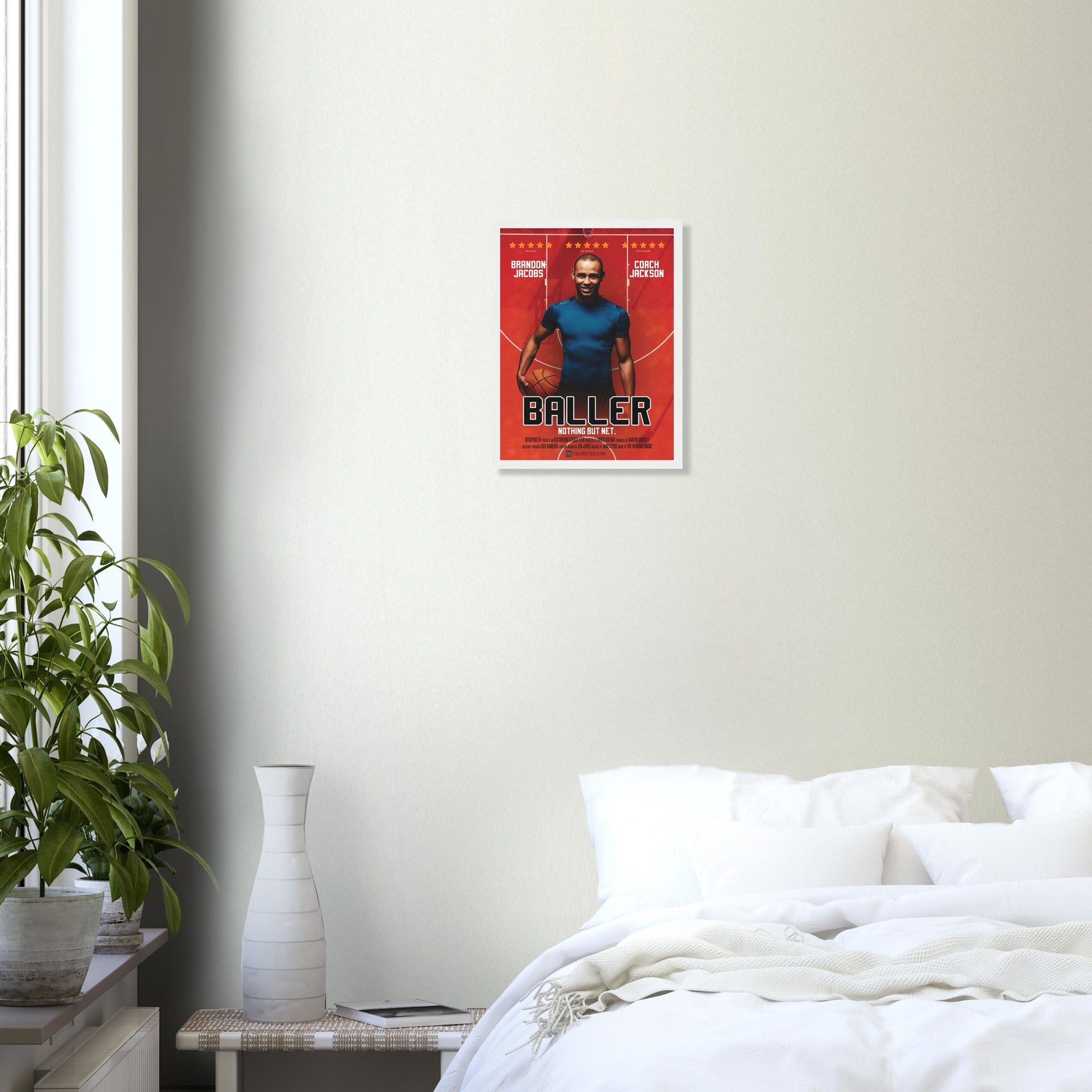 A custom basketball movie poster in a small white frame on a grey wall above a white bed and plant