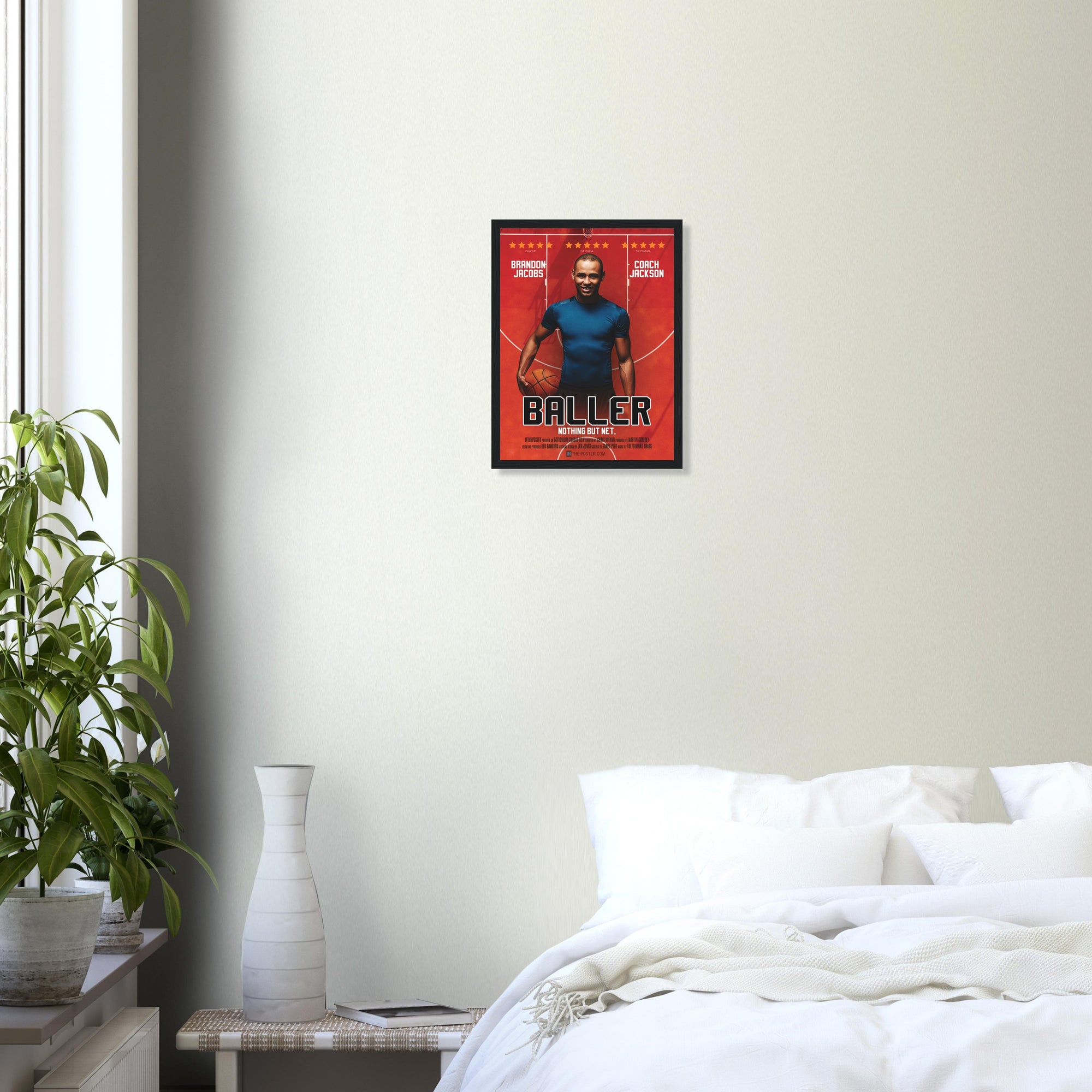 A custom basketball movie poster in a small white frame on a grey wall above a white bed and plant