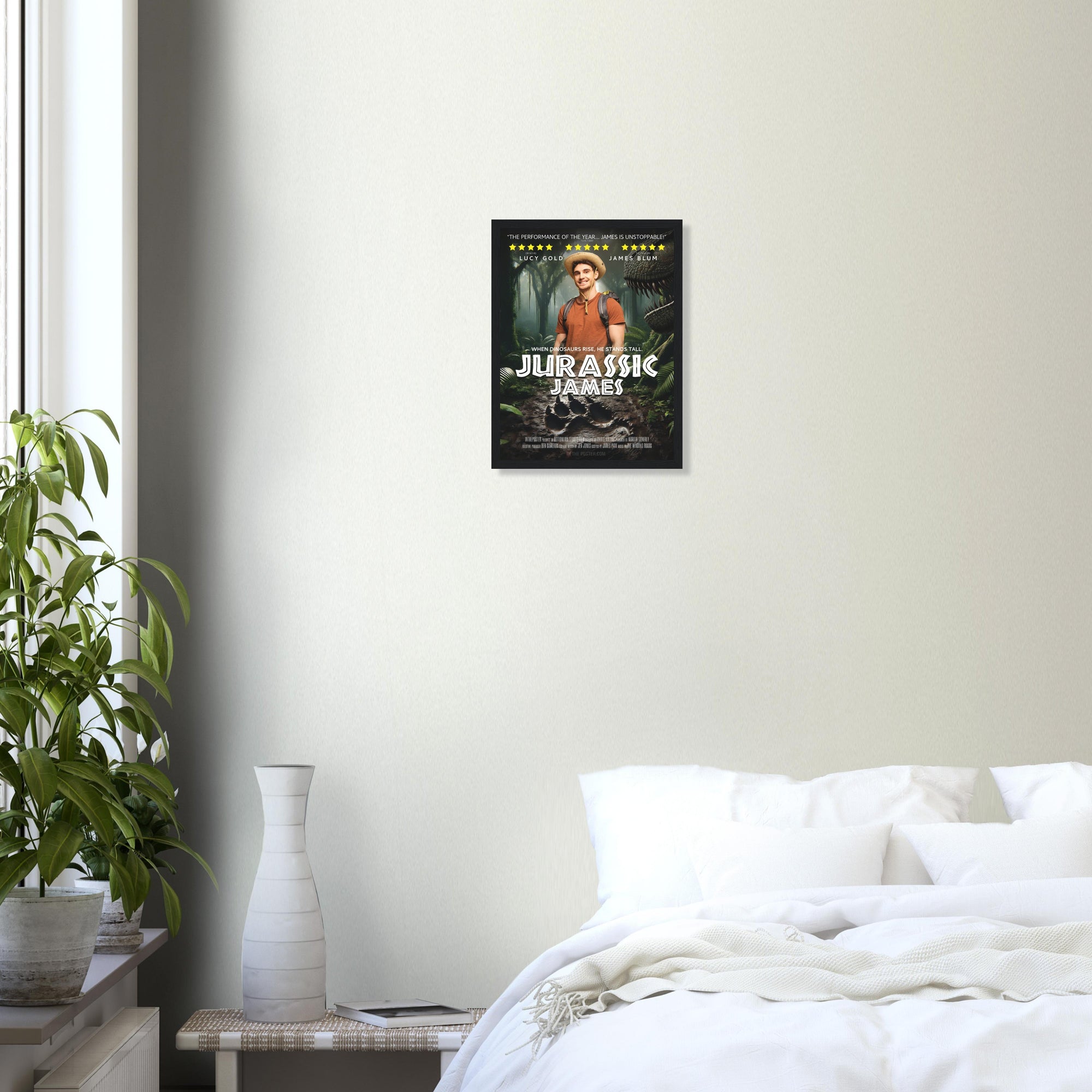 A small custom dinosaur-themed movie poster in a black frame is on a grey wall above a plant and a white bed.