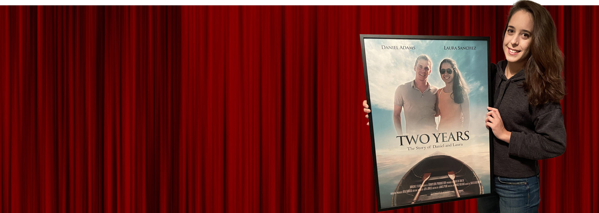 Smiling women with long beautiful brown hair holds a black framed custom movie poster featuring a photo of herself