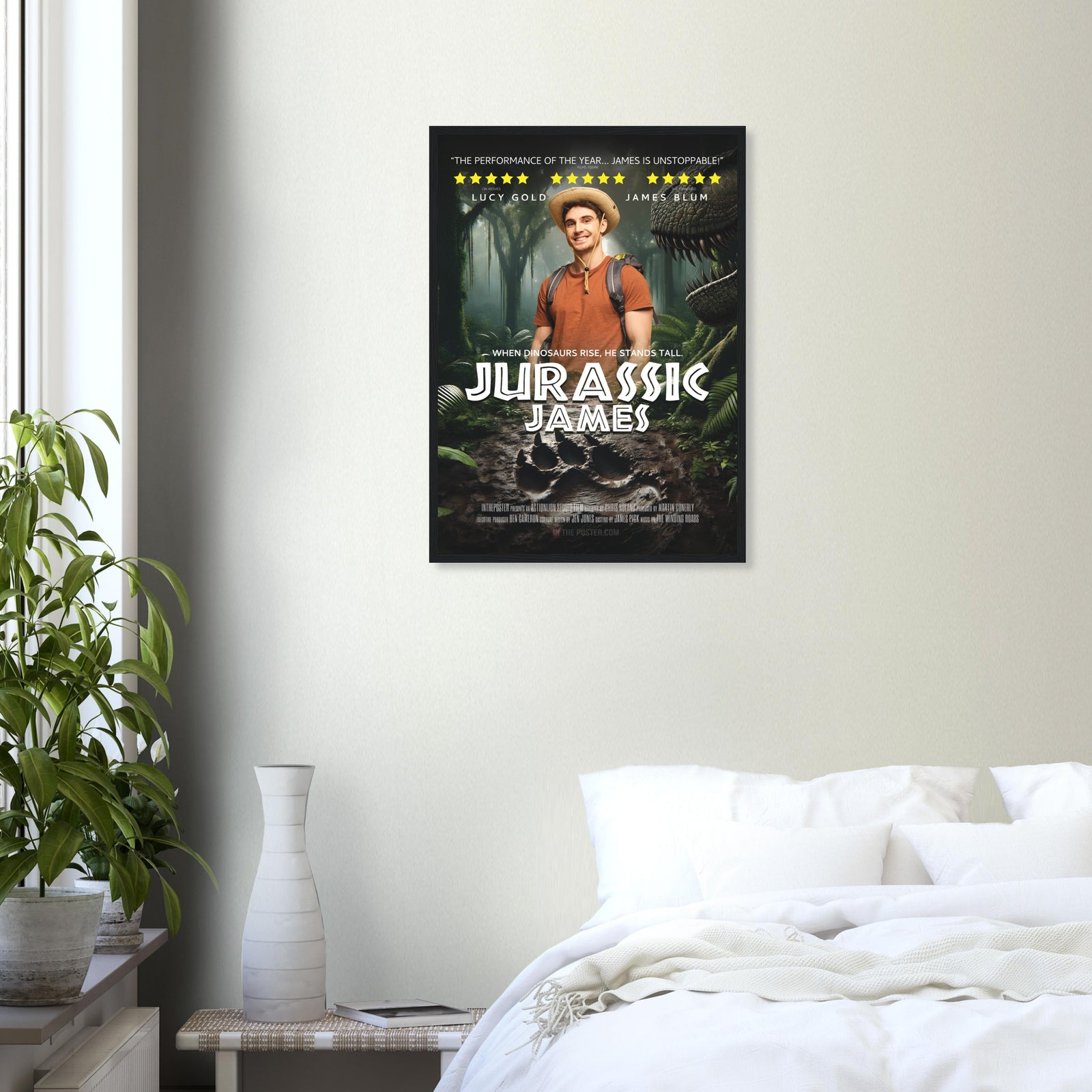 A dinosaur movie poster in a black frame is on a grey wall above a plant and a white bed.