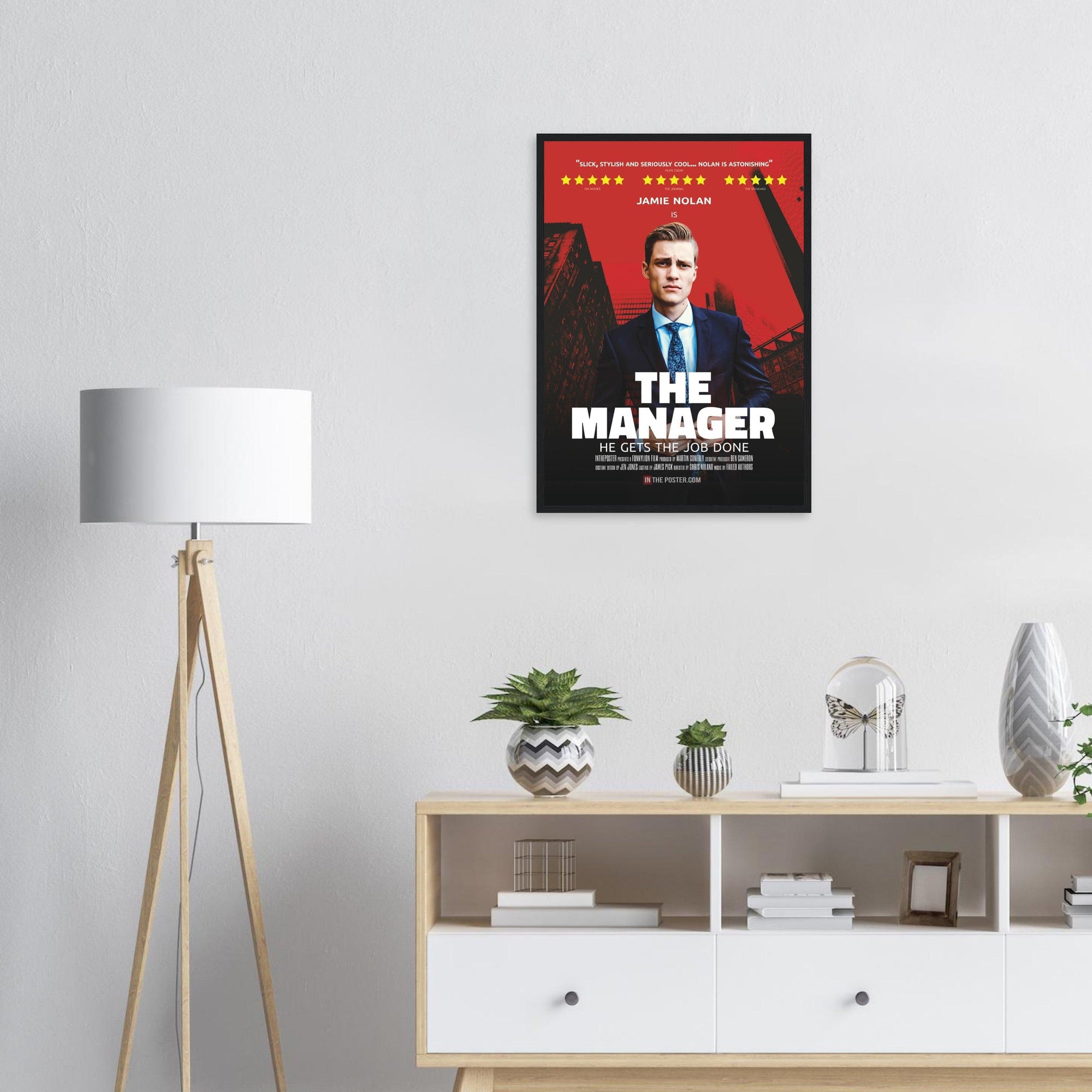 The Manager black regular framed movie poster on the wall above a cabinet and next to a stylish lamp