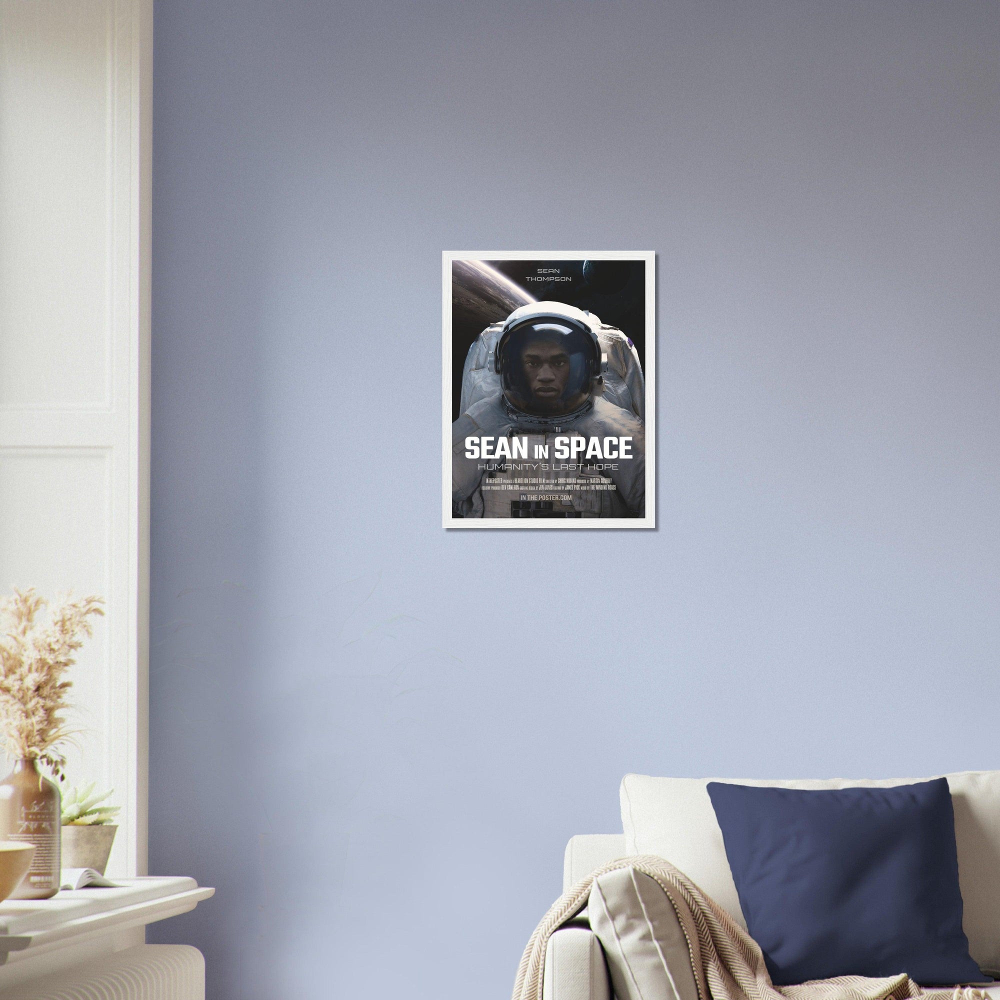 An astronaut sci-fi movie poster design in a small white frame on a blue wall above a designer sofa