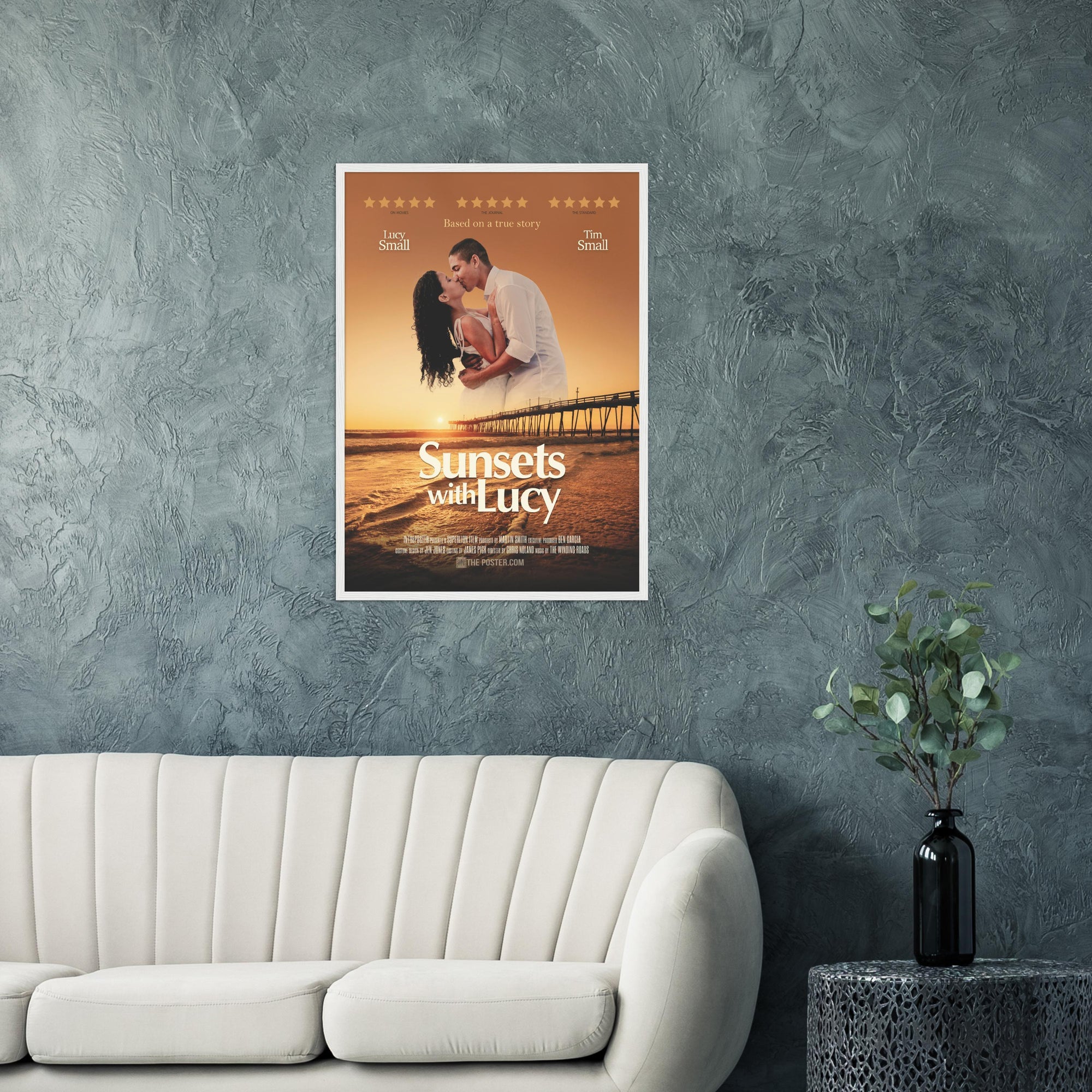 A custom movie poster in a white frame on the wall above a cream sofa