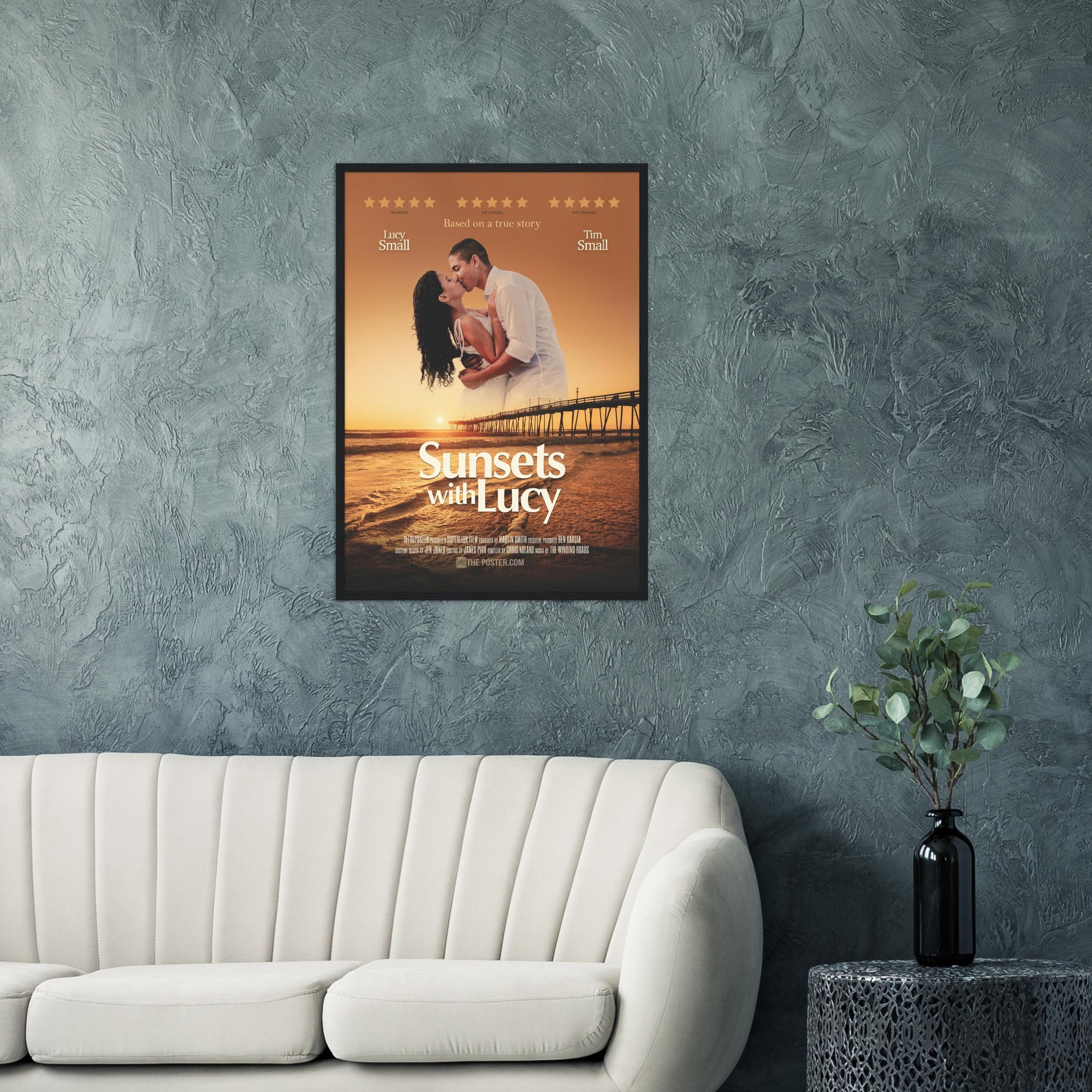 A custom movie poster in a regular sized black frame on the wall above a cream sofa