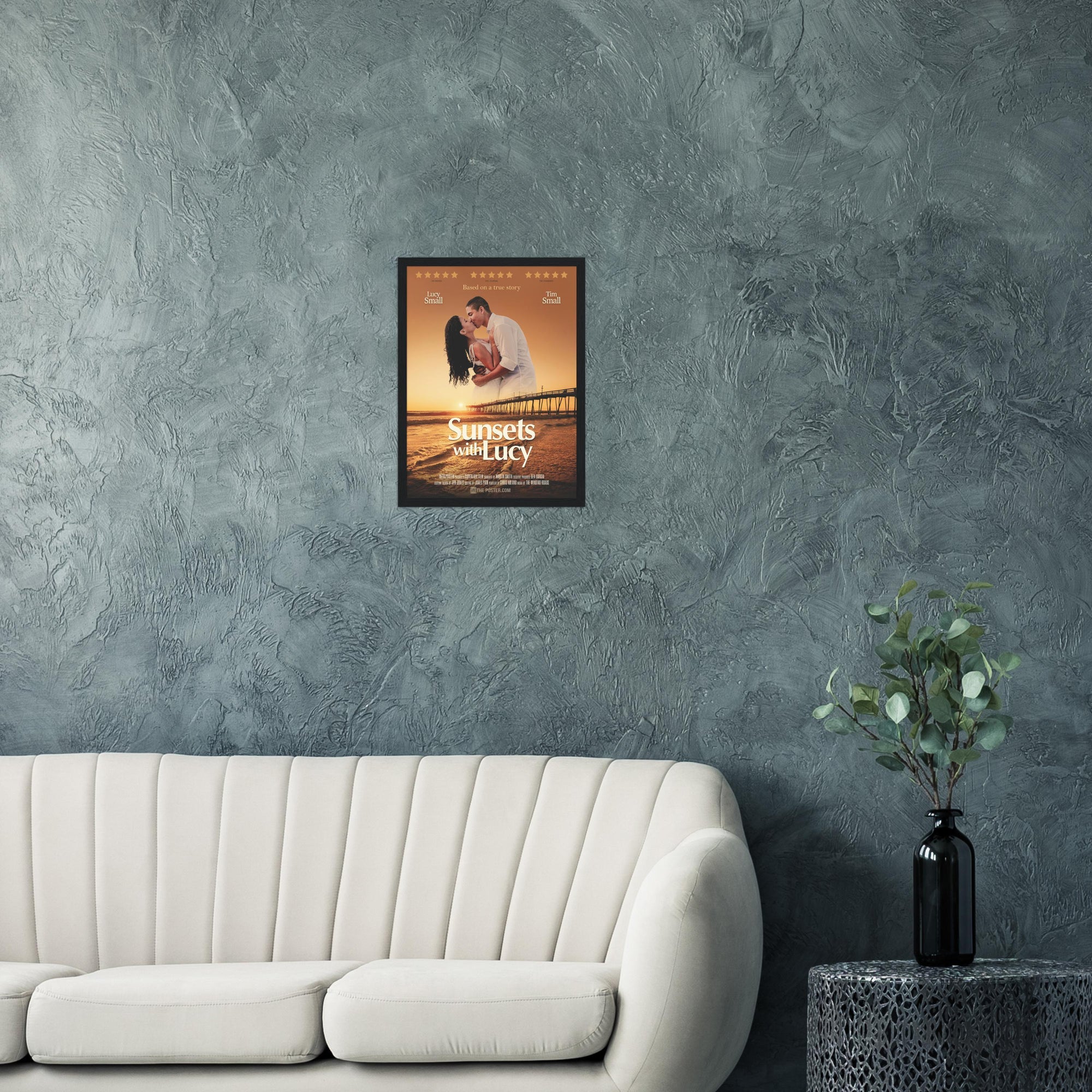 A custom movie poster in a small black frame on the wall above a cream sofa