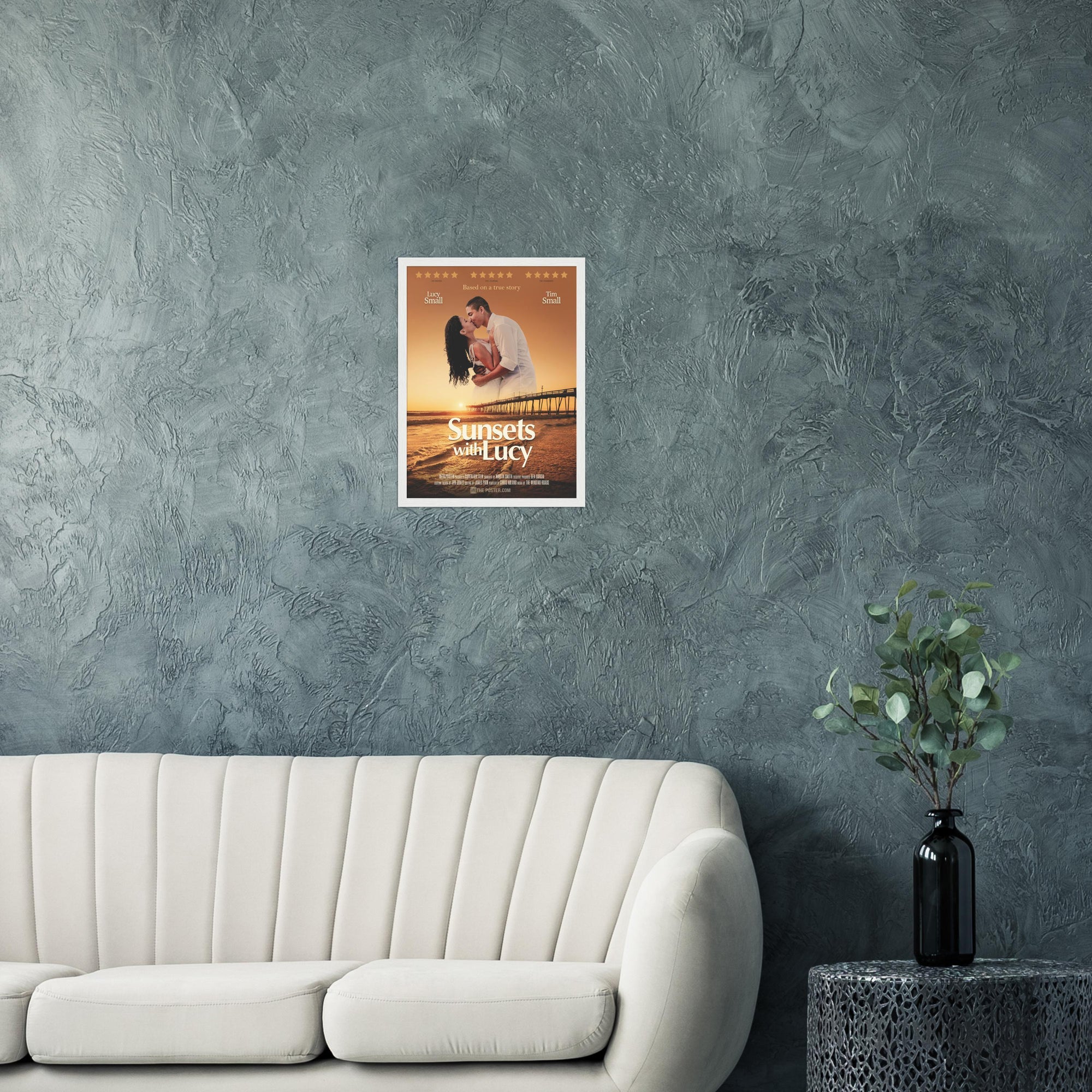 A custom movie poster in a small white frame on the wall above a cream sofa